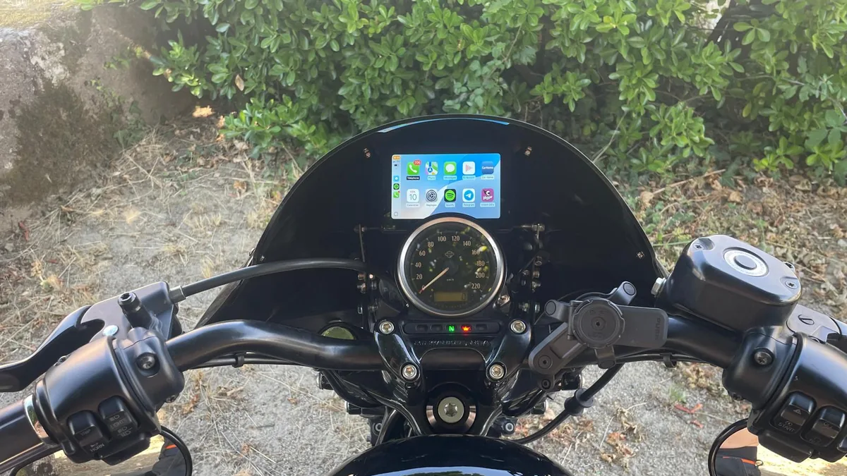 Carpuride 502H affichant l'&eacute;cran d'accueil Apple CarPlay avec Spotify sur un tableau de bord Harley-Davidson