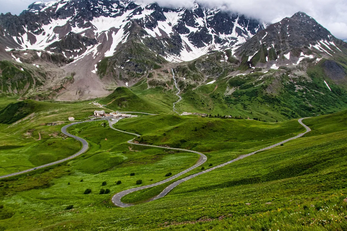 Route sinueuse du Col du Galibier avec sommets enneigés